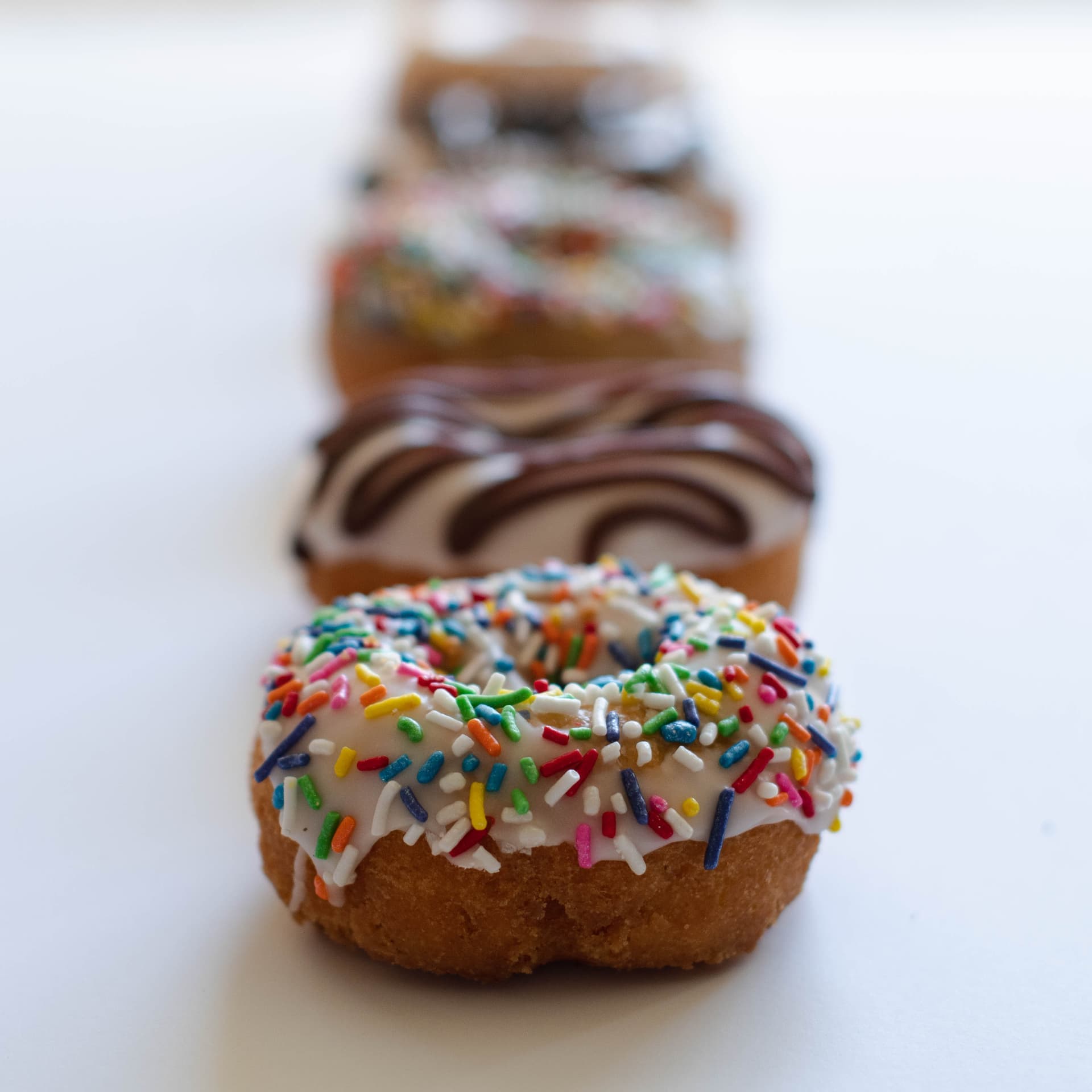 Row of vegan donuts with various toppings in artistic focus