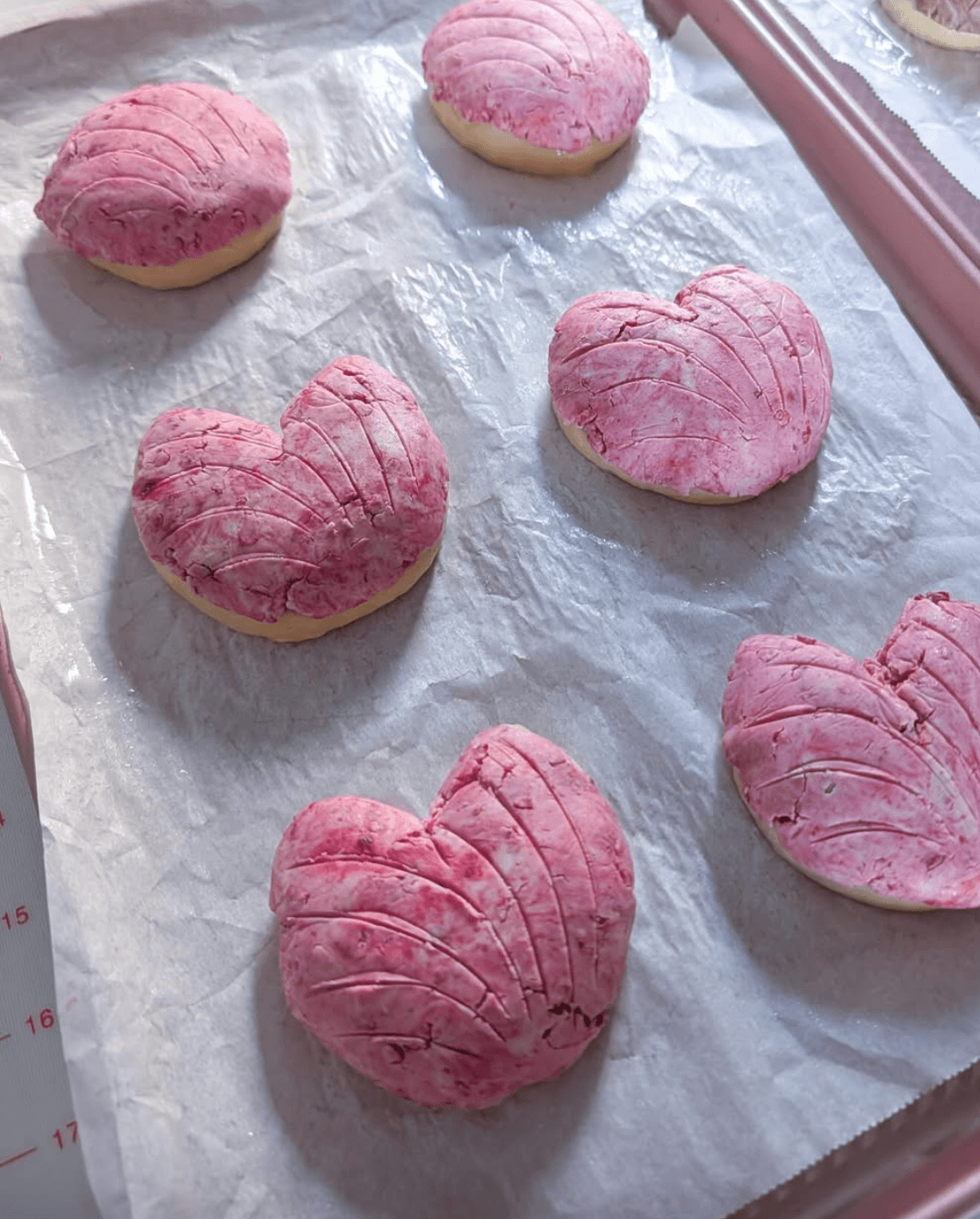 Heart-shaped conchas on a baking sheet